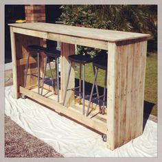 an outdoor bar made out of pallet wood with three stools on the top