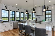 a large kitchen with lots of windows and chairs