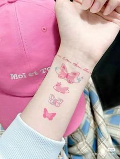 a woman with a pink hat and butterfly tattoo on her arm is holding onto a baseball cap