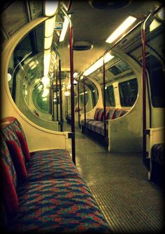 the inside of a subway car with seats and mirrors on it's walls,