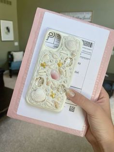 a person holding up a phone case with shells and seashells on it