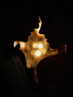 a couple kissing in front of the eiffel tower at night with lights behind them