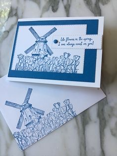 two cards with blue ink on them, one has a windmill and the other has flowers