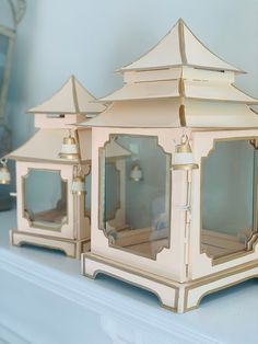 two white lanterns sitting on top of a shelf