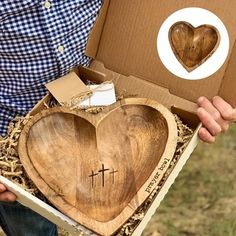 a person holding a box with a wooden heart and cross cut out in the middle