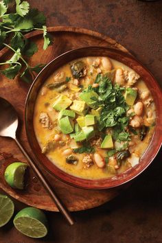 a bowl of soup with beans, avocado and cilantro on the side