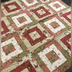 a quilted table topper with red and green flowers on it's sides