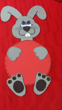 a paper cut out of a rabbit with big ears and legs sitting on a red surface