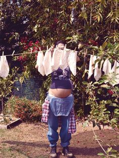 a man standing in front of a tree with clothes hanging from it's line