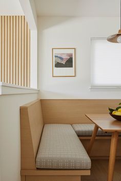 a bowl of fruit sitting on top of a wooden table next to a bench in a room