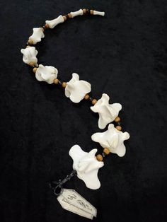 a necklace with white flowers and brown beads on a black cloth covered tablecloth,