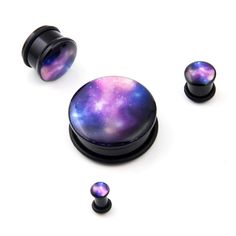 two black acrylic ear plugs with purple and blue galaxy design on them