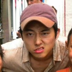 three people are posing for the camera with one man wearing a hat and another woman in an orange shirt