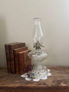 a glass lamp sitting on top of a wooden table next to books and a book