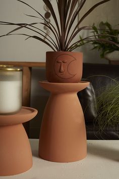 two clay pots sitting on top of each other next to a candle holder and potted plant