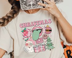 "Embrace the festive spirit in style with our vibrant collection featuring the \"Pink Christmas Vibes Shirt,\" \"Retro Christmas Shirt,\" \"Pink Santa Sweatshirt,\" \"Funny Merry Christmas Shirt,\" and the \"Santa Tree Ornaments Presents Shirt.\" Each piece encapsulates the joy and playfulness of the holiday season, offering a unique blend of retro vibes and merry cheer. Perfect for those who adore a touch of humor and a splash of color in their holiday wardrobe, our collection is designed with high-quality materials and a comfortable fit, ensuring a jolly experience for any occasion.  Materials → All our simple color ones like White and Black are 100% Cotton. → All our Heathered Colors are cotton/polyester blend and they are super comfy soft! → Soft and High-Quality Fabric → Sueded Jersey Funny Merry Christmas, Personalized Christmas Shirts, Retro Christmas Shirt, Santa Tree, Merry Christmas Funny, Pink Santa, Santa Sweatshirt, Christmas D, Merry Christmas Shirts