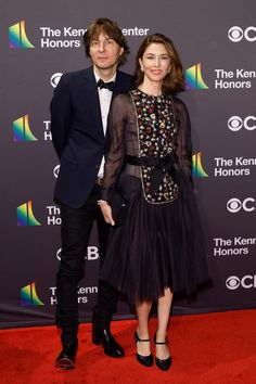 a man and woman standing next to each other on a red carpet