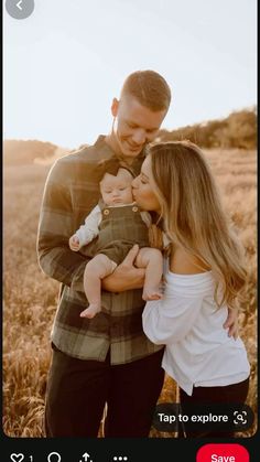 a man holding a baby while standing next to a woman with her arms around him