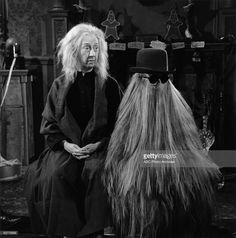 an old man with long hair sitting next to a woman in a wig on the set of