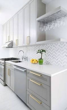 a kitchen with white counter tops and gold trim on the cabinets, along with a potted plant