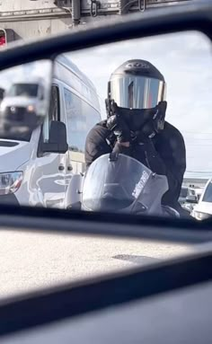 the reflection of a man in a side view mirror wearing a motorcycle helmet and protective gear