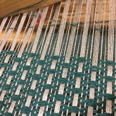 a close up view of a weaving machine with green and white yarn on the table