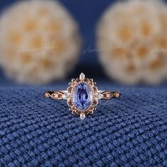 an oval shaped tan and white diamond ring sits on top of a blue cloth with two smaller round diamonds in the background