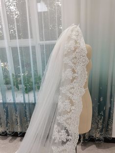 a white wedding veil on a mannequin in front of a window