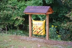 a yellow bag sitting on top of a wooden stand in front of some green trees