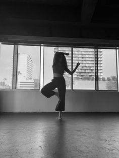 a woman standing on one leg in front of a window