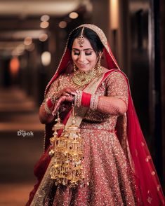 a woman in a red and gold bridal outfit holding a golden birdcage