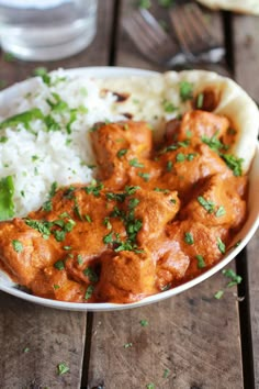 a white bowl filled with rice and meat covered in cilantro sauce on top of a wooden table