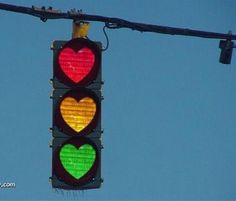 a traffic light with two hearts painted on the red, green and yellow lights above it