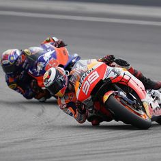 two motorcyclists are racing on the track during a race, one is leaning forward