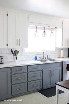 a kitchen with gray cabinets and white counter tops