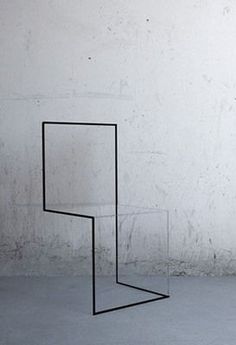 a black metal shelf sitting on top of a cement floor next to a white wall