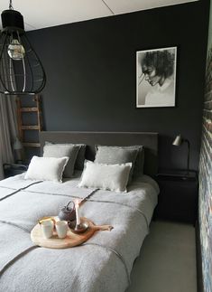 a bed with white pillows and blankets on it, next to a brick wall in a bedroom