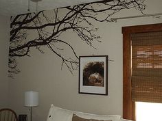 a living room with white couches and tree branches painted on the wall above them