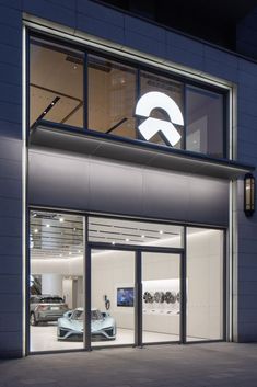 a car showroom with cars in the window and an illuminated logo on the wall