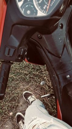 a person's feet resting on the handlebars of a motorbike