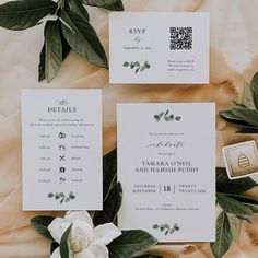 the wedding stationery is laid out with flowers and greenery on top of it