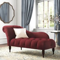 a red chair sitting on top of a rug in front of a window with blue drapes