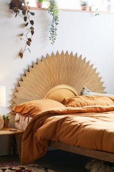 a bed with an orange bedspread in a bedroom next to a window and potted plants