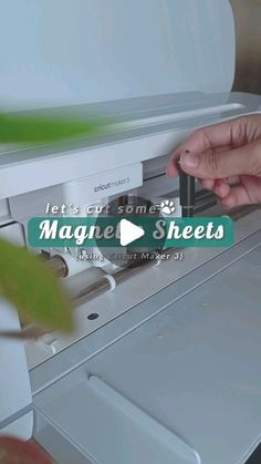 someone inserting the magnets on top of a white refrigerator with green leaves in it