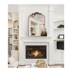 a living room with a fire place and bookshelves on the wall above it