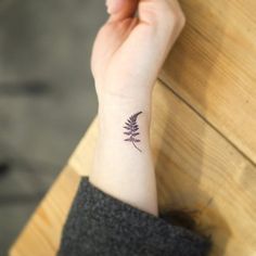 a woman's wrist with a small tattoo on her left arm, and a flower in the middle