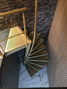 a spiral stair case next to a brick wall