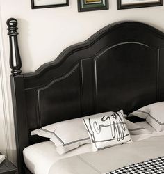 a black headboard with white pillows and pictures on the wall