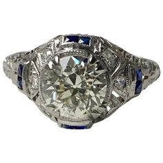 an old cut diamond ring with blue sapphires on the sides and side stones in the center