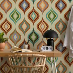 a table with a lamp and a book on it in front of a wallpaper